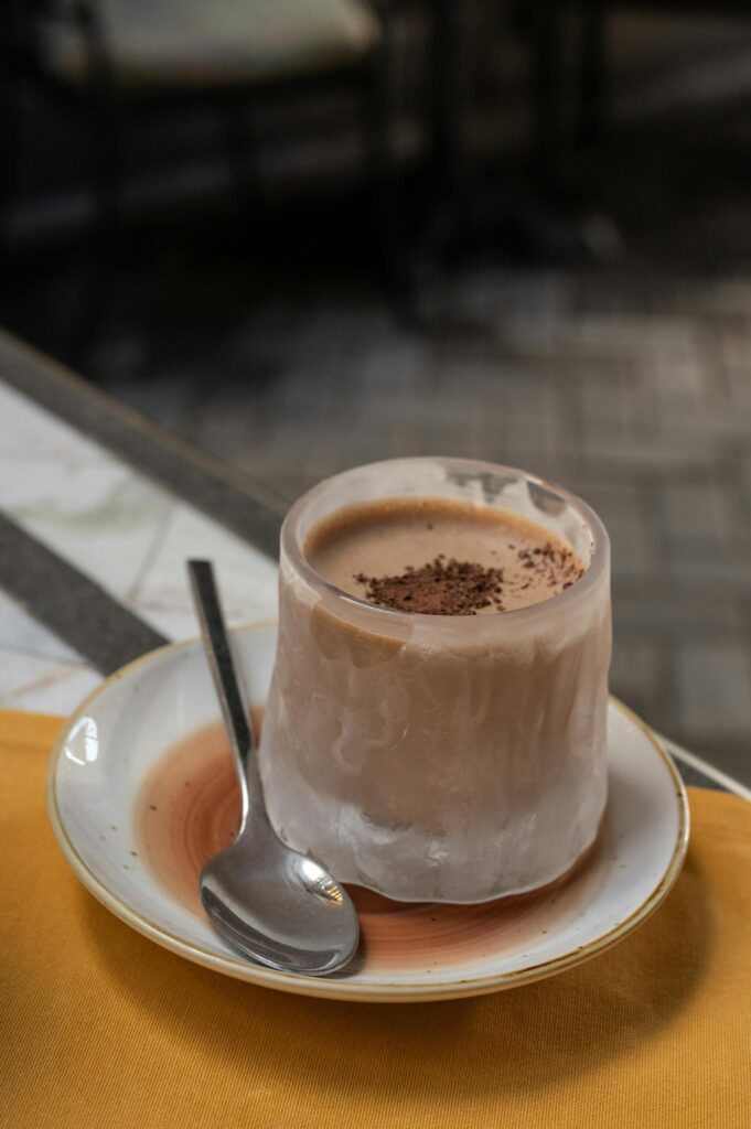 Chilled cappuccino served in a frozen glass with chocolate flakes on top at an outdoor cafe setting.